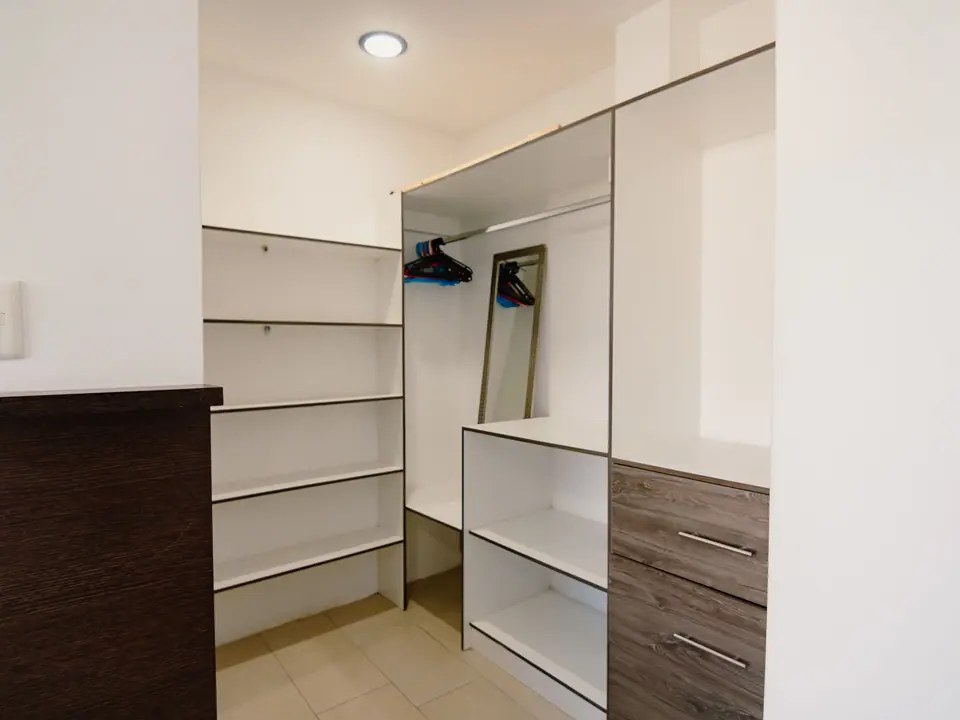El clóset abierto de un dormitorio de CASA A12, con repisas, cajones y ganchos.