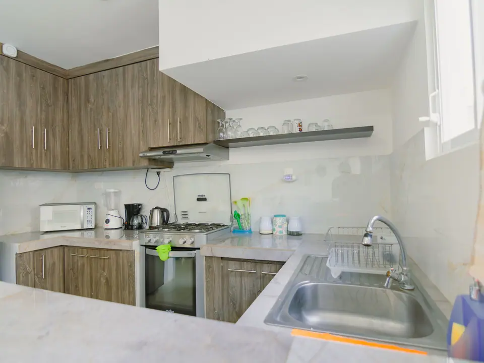 La cocina de CASA A12: muebles de madera, cocina a gas con horno, microondas y cafetera.