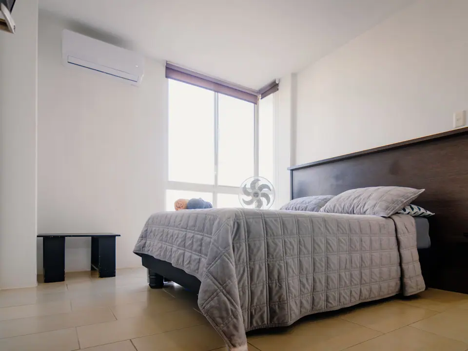 El mismo dormitorio de CASA A12 visto desde la puerta, con la cama doble y una banca.