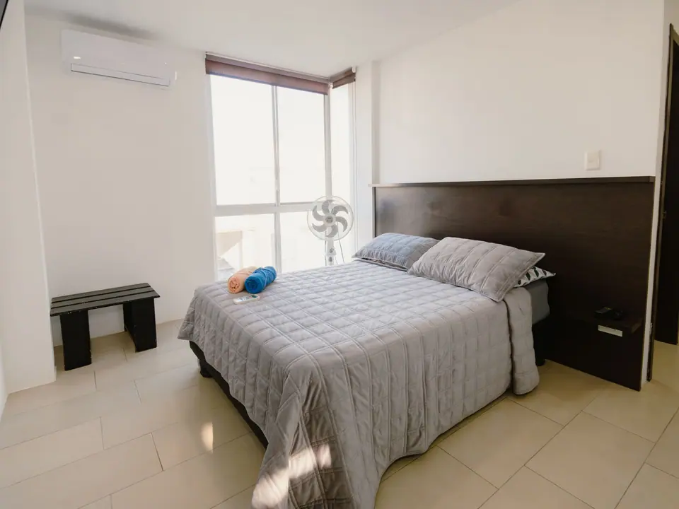 Dormitorio de CASA A12 con cama doble, aire acondicionado y ventana de piso a techo.