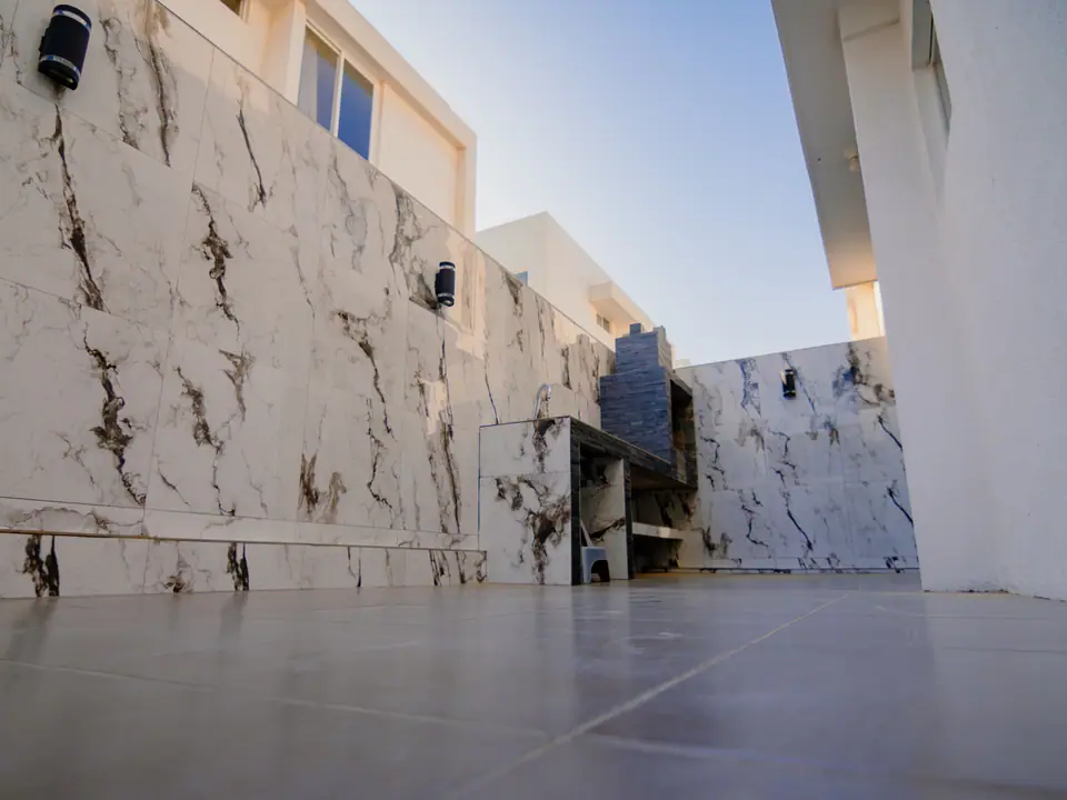 El patio de CASA A12, con paredes de porcelanato y la parrilla de carbón.