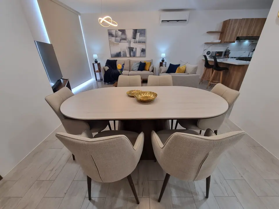 La mesa de comedor de cerca, con sus sillas tapizadas en beige.