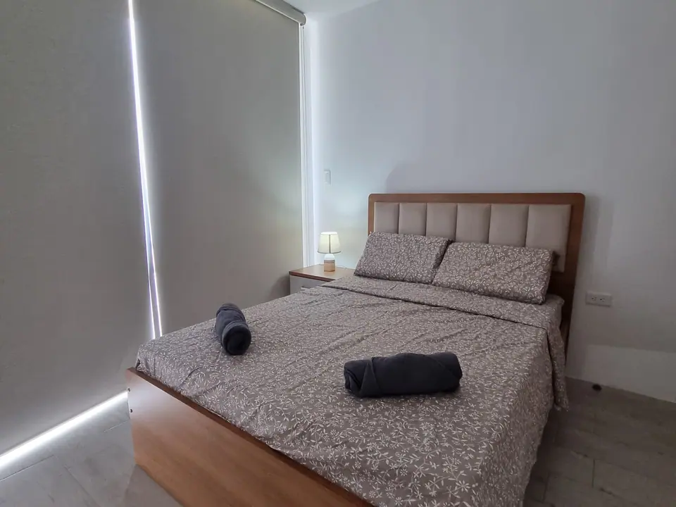 Un dormitorio con cama doble y cortina que oscurece el cuarto.