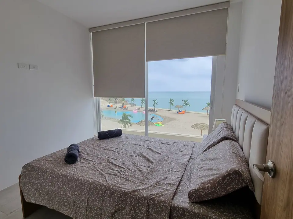 Un dormitorio con cama doble y una ventana por la que se ve el mar.