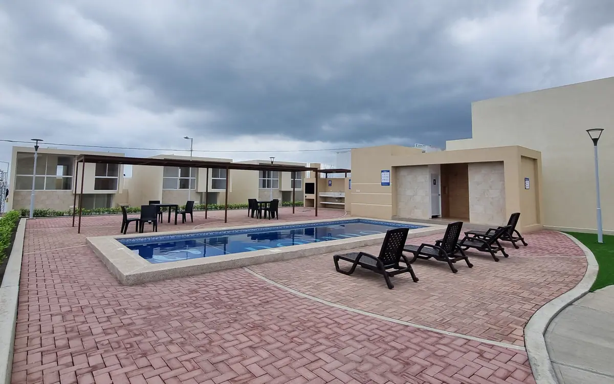 La piscina de la urbanización Punta Arrecife, con tumbonas y mesas a la sombra de una pérgola.
