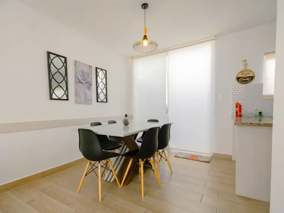 El comedor de CASA C5, con mesa de mármol y sillas negras.