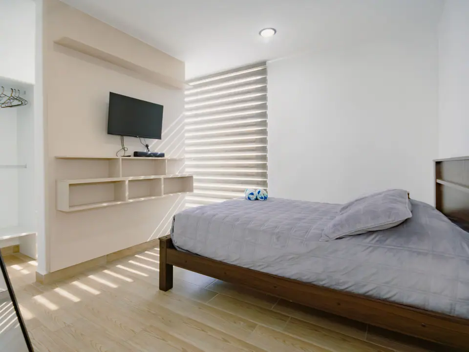 El dormitorio principal de CASA C5, con su televisor y las persianas enrollables.