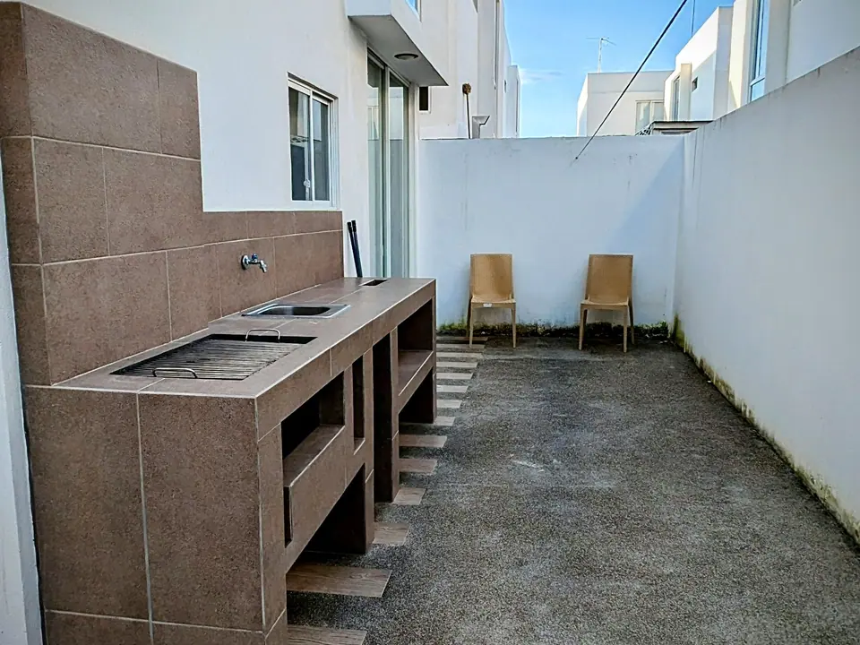 El patio de CASA C5, con la parrilla de obra y dos sillas.