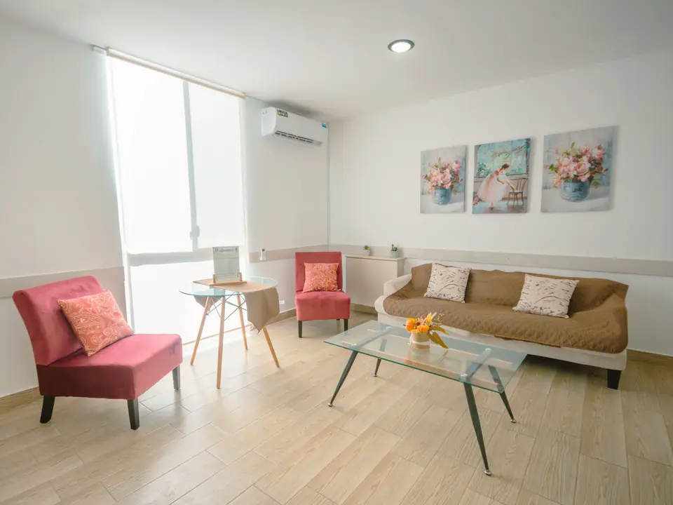 La sala de CASA C5 vista hacia la ventana, con aire acondicionado y tres cuadros.