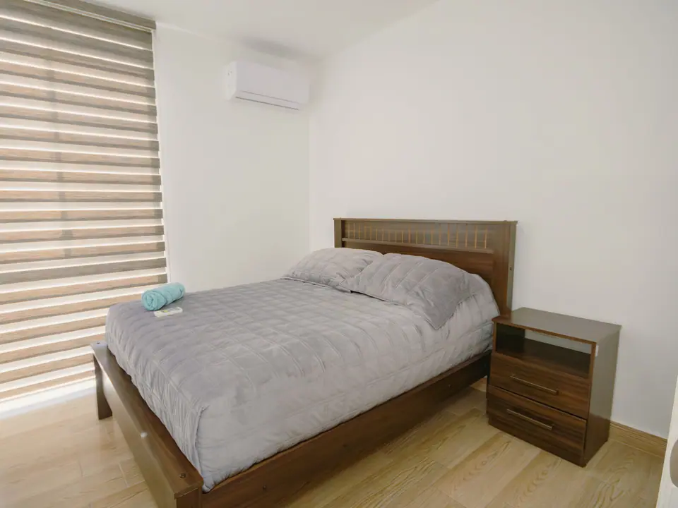 Dormitorio de CASA C5: cama doble, aire acondicionado sobre la ventana y persianas enrollables.