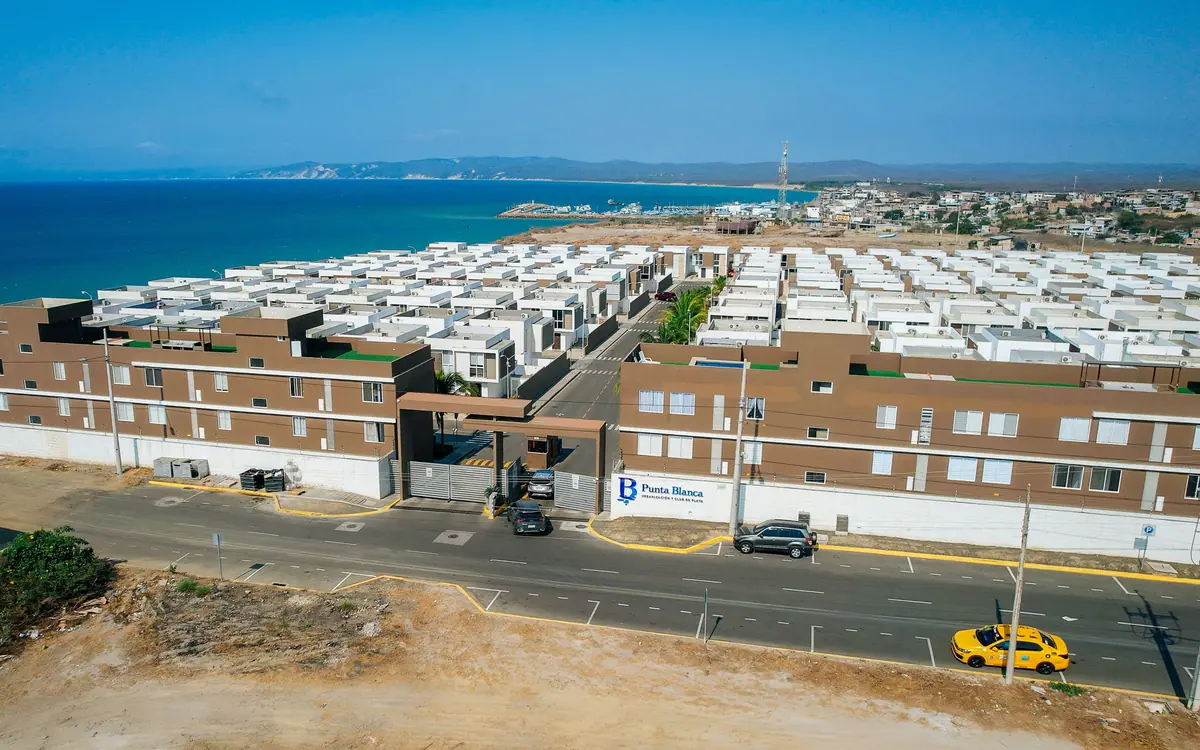 El edificio de entrada de la urbanización Punta Blanca, con el mar detrás de las casas.
