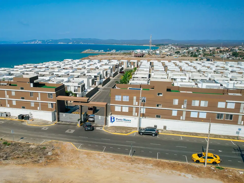 El edificio de entrada de la urbanización Punta Blanca, con el mar detrás de las casas.