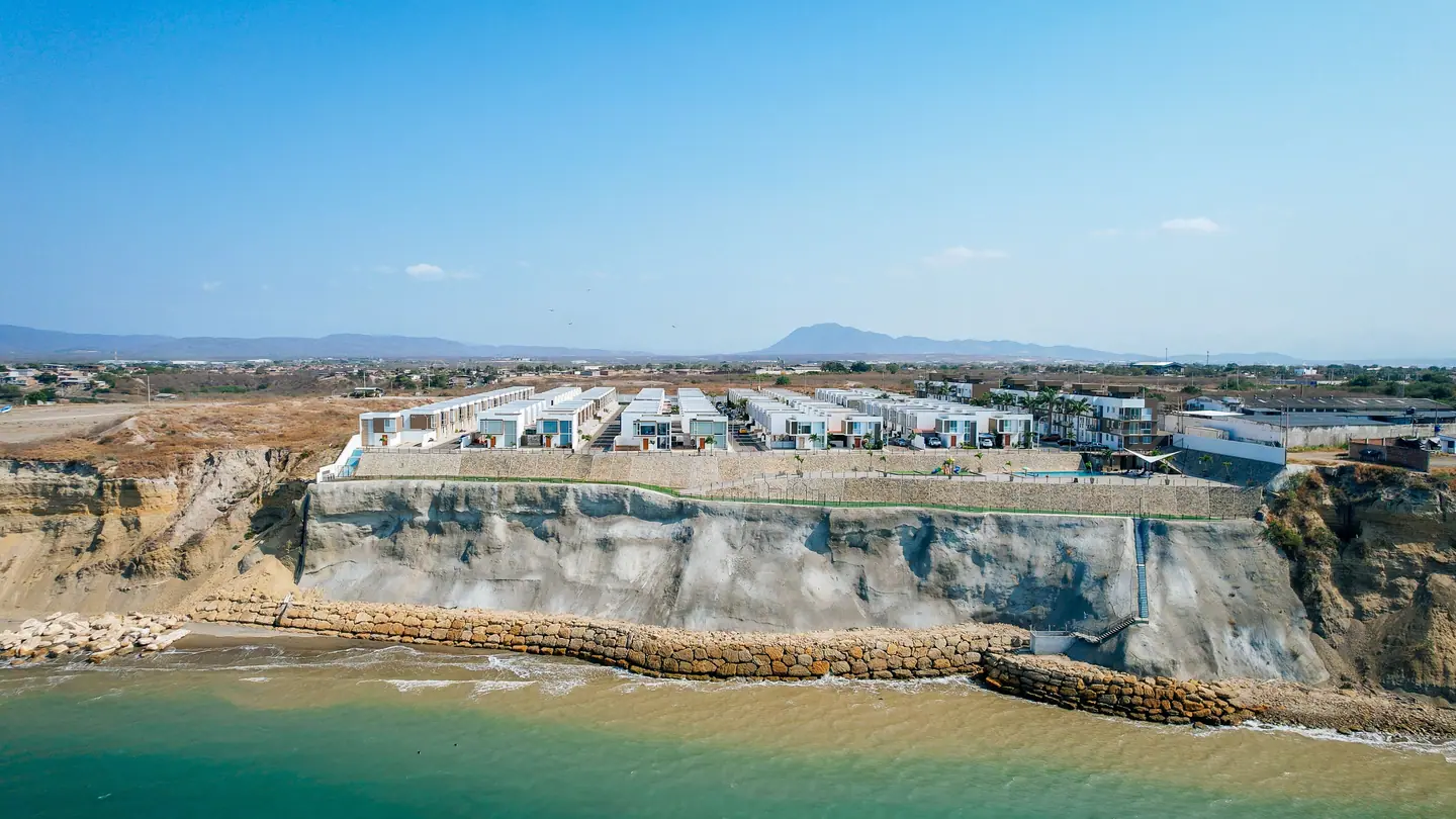 La urbanización Punta Blanca vista desde el mar: casas blancas sobre un acantilado claro, con la bahía de Jaramijó al pie.